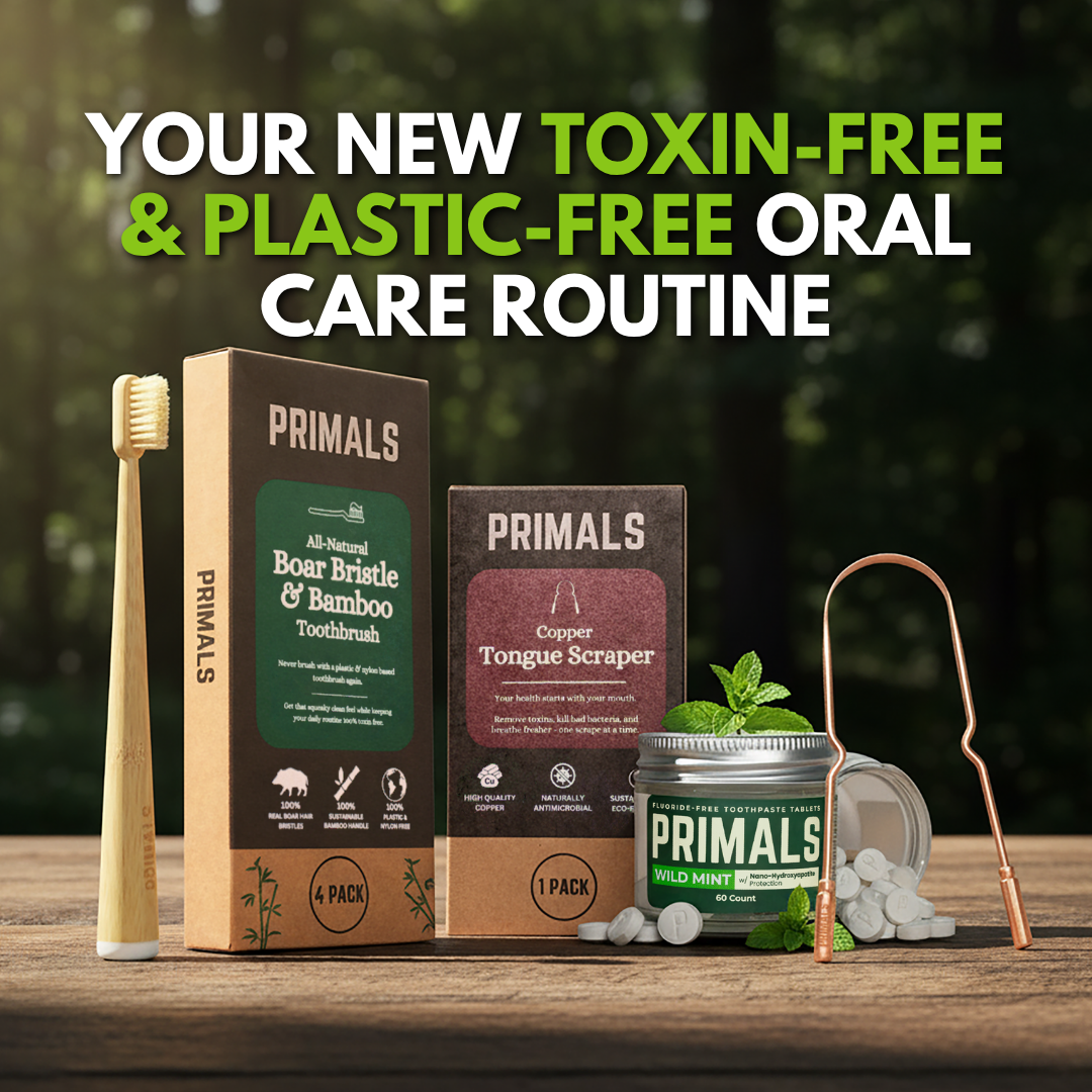 PRIMALS Boar Bristle & Bamboo Toothbrush, Copper Tongue Scraper, and Toothpaste Tablets on a wooden table.